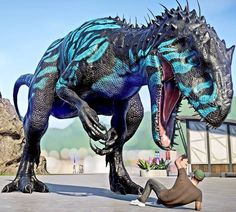 a man kneeling down in front of a large dinosaur with it's mouth open