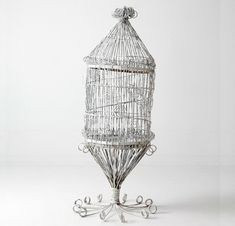 a white bird cage sitting on top of a metal stand