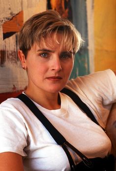 a woman sitting in a chair with a camera around her neck and looking at the camera