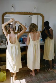 two women standing in front of a mirror brushing their hair