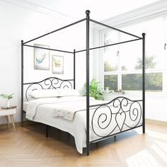 a white bed sitting in a bedroom on top of a hard wood floor next to a window