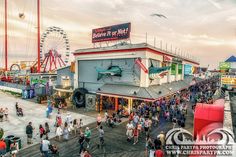 a crowd of people standing on top of a pier next to a ferris wheel