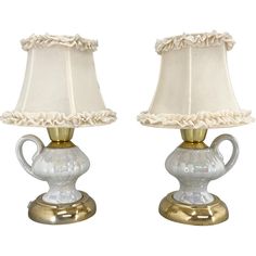 two white lamps with gold trim on them