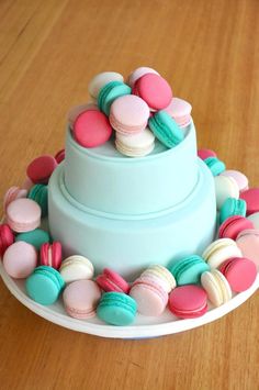 a cake with macaroons on it sitting on top of a wooden table next to a cupcake