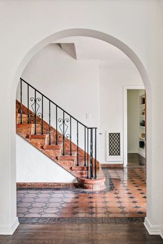 an archway leading to a staircase in a house with tiled flooring and wooden handrails