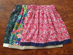 four different colored skirts sitting on top of a wooden floor