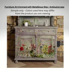 an old dresser painted with flowers and plants on the front, next to a stone wall