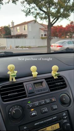 two little yellow people sitting on the dashboard of a car with an ad in front of them