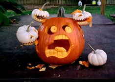 a carved pumpkin with an evil face and two smaller pumpkins sitting on top of it