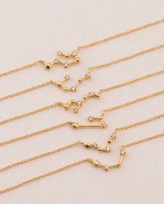 five gold necklaces with different designs on them