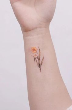 a small wrist tattoo with flowers on the left side of the arm and an orange flower in the middle