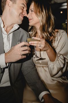 a man and woman sitting next to each other holding wine glasses