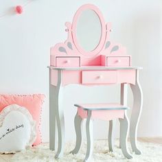 a pink vanity with mirror and stool in a white room next to a teddy bear