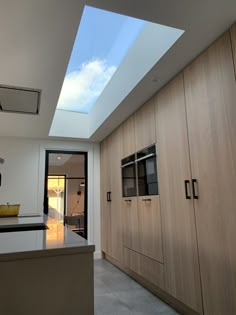 an open kitchen with skylight above the countertop and cupboards on either side