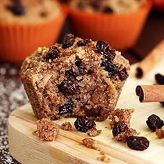 a muffin on a cutting board with raisins and cinnamon in the background