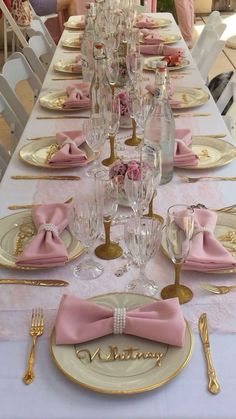 the table is set with pink and gold place settings