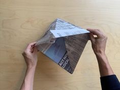 a person is holding an origami piece of paper in front of a wooden wall