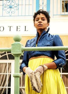 a woman in a blue shirt and yellow skirt is holding a snake on her hand