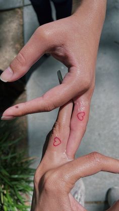 two people holding each other's hands with hearts painted on their thumbnails