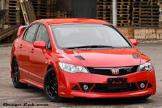 a red car parked in front of some pallets