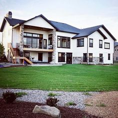 a large white house sitting in the middle of a lush green field next to a stone bench