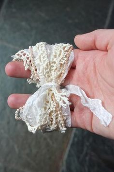 a hand holding two pieces of white fabric