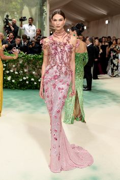 a model walks the runway in a pink and green gown with sequins on it