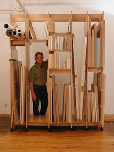 a man standing in the doorway of a book shelf filled with books and papers on wheels