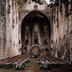 an old church with rows of chairs and flowers on the aisle