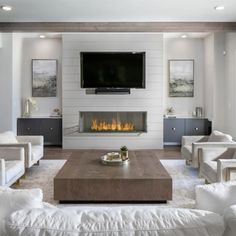 a living room with white furniture and a flat screen tv mounted above the fire place