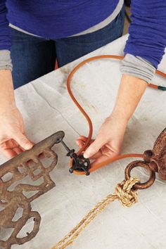 a woman is working on an old rusty object with chains and other items around her