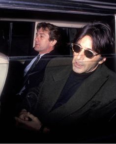 two men sitting in the back of a car, one with sunglasses on his head