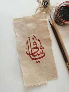 a piece of paper with the words in arabic on it next to two pencils