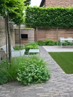 a brick walkway leads to an outdoor seating area with lawn and chairs in the background