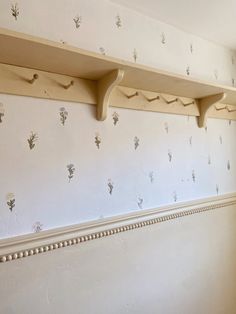 two wooden shelves on the wall with flowers painted on them and beaded trim around the edges