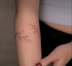 a woman's arm with a small branch tattoo on it