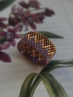 a close up of a ring on a table with flowers in the background and an open book