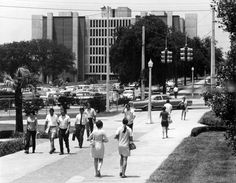 black and white photograph of people walking down the sidewalk