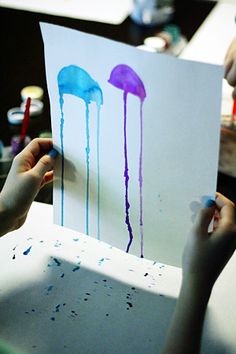 two children are painting jellyfish on paper with colored watercolors in front of them