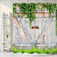 an open wooden door with green plants on the outside and lights in the inside behind it