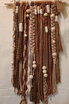 a wall hanging made out of different types of yarn and wooden bead beads on a white background