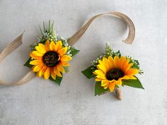 two sunflower boutions with baby's breath tied to them on a white surface