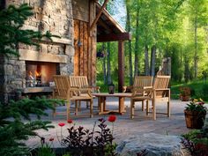 a patio with chairs and a table in front of a fire place surrounded by trees