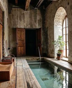 an indoor swimming pool in the middle of a stone building with wooden floors and windows