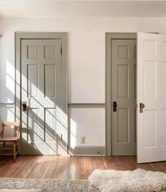 an empty room with three doors and a rug on the floor