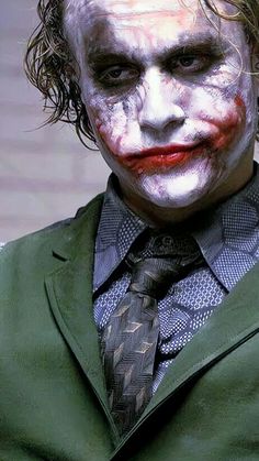 a man dressed up as the joker in a suit and tie with his hair pulled back