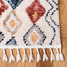 a multicolored rug with tassels and fringe on the wooden flooring