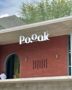 a man is standing on the balcony of a red brick building that says po - kak