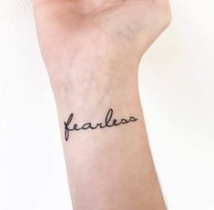 a woman's wrist tattoo with the word fearless written in cursive font