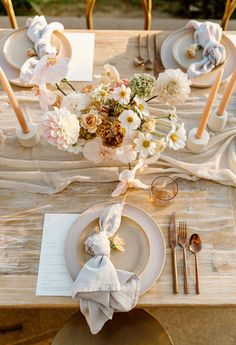 the table is set with plates, silverware and flowers